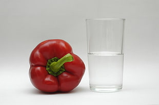 red bell pepper beside drinking glass filled with water